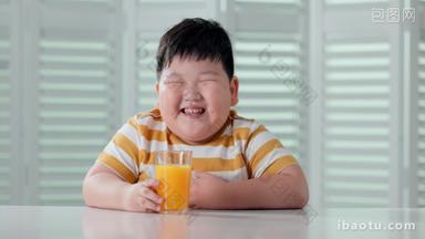 快乐的小胖男孩喝橙汁